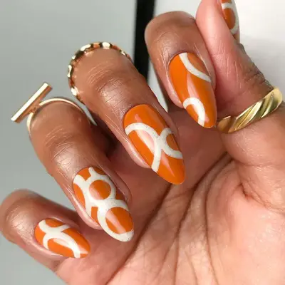 a burnt orange manicure with white circle nail art