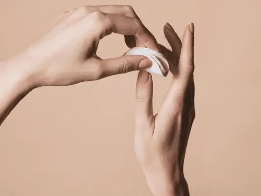 Hands holding cotton rounds to take off nail polish