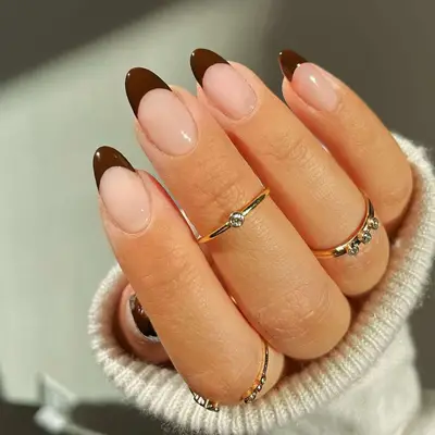 Hand with brown French manicure and gold rings
