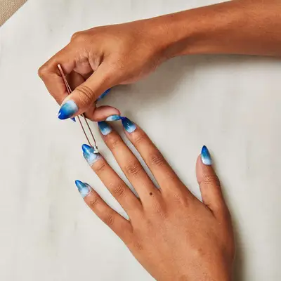 A woman adds details to her ombré nail polish