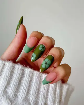 Close-up of green manicure with floral designs and French tips