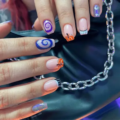 Short square nails with mismatched designs, including pumpkin french tips and swirls.