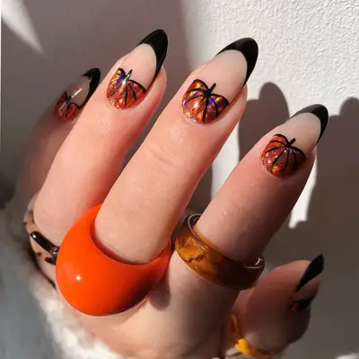 Close up of nude nails with black French tips and rainbow chrome pumpkin art.