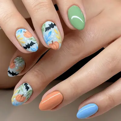 Close up of pastel colored ails with bat and pumpkin designs on accent nails.
