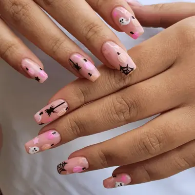 Close up of nude square nails with pink pumpkin, ghost, and spider handpainted details.