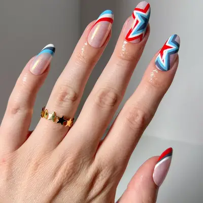 Iridescent neutral nails with red, white, and blue stripes and star-shaped designs