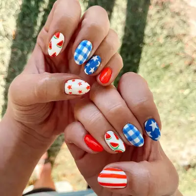 Close up of mismatched nails with red, white, and blue gingham, star, and stripe patterns