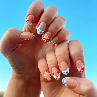 Close up of mismatched Fourth of July French manicure, with gingham, cherry, and daisy print