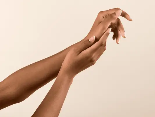  African American female with French manicure touching hand gently on beige background