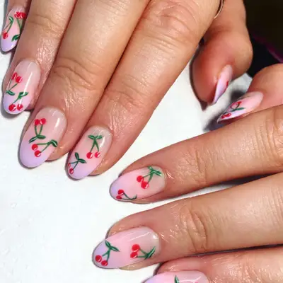 Hand with purple ombre French manicure with hand-painted mini cherries.