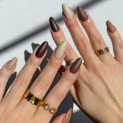 model with matte brown, taupe, and cream nails