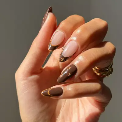 model with brown nails with orange stripes and small daisies