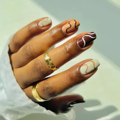 model with brown nails with coordinating wavy lines in a contrasting color