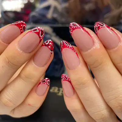 model with bare nails and red French tip with paisley details in white and black