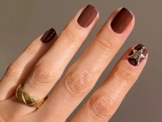 Warm brown manicure with silver star charm on index finger