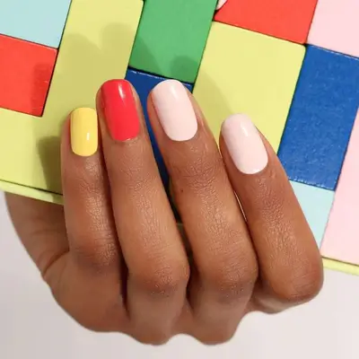 A mani with yellow, red, and peach-colored nails