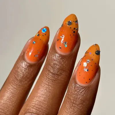 bright orange syrup nails with chunky silver glitter