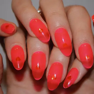 neon pink nails with red heart decals underneath