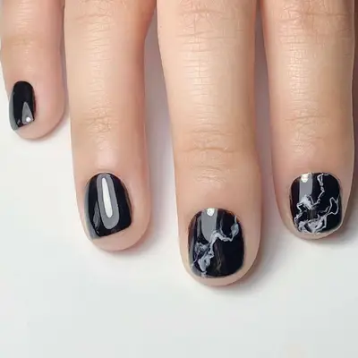 Short black nails, two with subtle white and gray marbling.