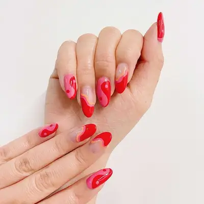 Peach, pink, and red nails with yin/yang and wave designs