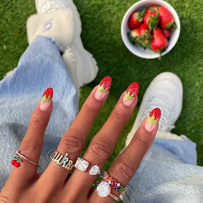 negative space manicure with red strawberry design tips and leafy stems near base