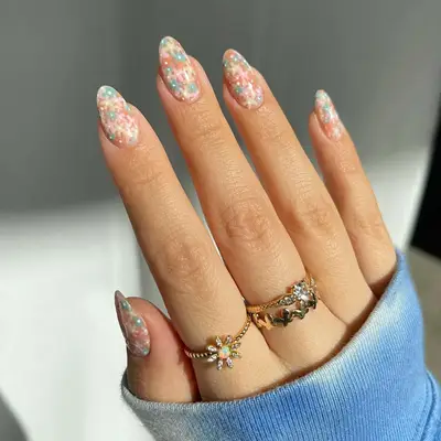 close up of nails with small flowers in pale hues like pink, orange, yellow, green, drawn very close together in clusters