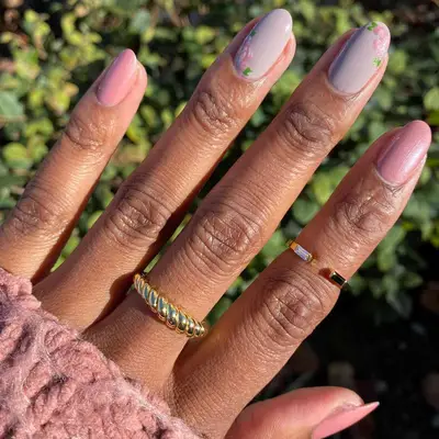 close up of nails with three fingers in pink sparkle sheen and two with nudey pink base with handpainted pink roses