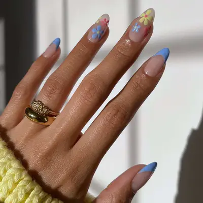 close up of nails with yellow, blue and pink flowers on 2 nails, and blue french tips on 3 remaining fingers
