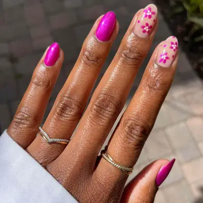 close up of nails with three painted in magenta color with two other nails having nude base with magenta hand painted flowers on top
