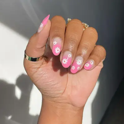 close up of nails with bare base and pink ombre tips with white flowers hand painted on top