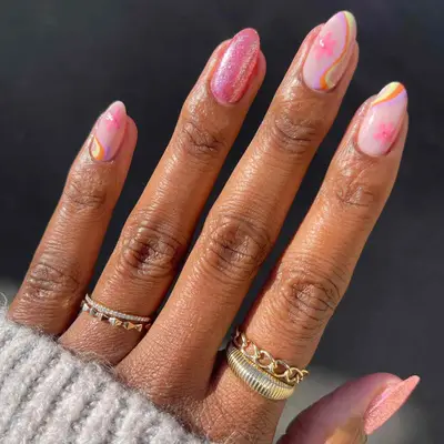 close up of nails with 2 plain sparkly pink nails and three nails with pale pink base with rainbow stripes and pink flowers