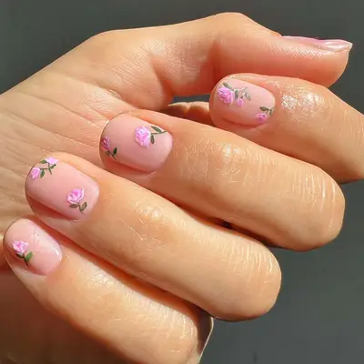 close up of nails with pale pink base and hand painted pink roses with green stems