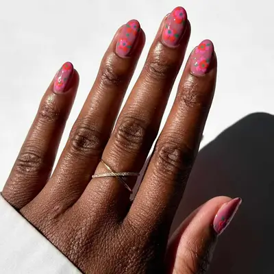 close up of nails with pink base and bright pink and orange flowers painted on top