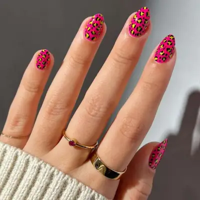 Short almond-shaped nails with a pink base and black and yellow cheetah print.