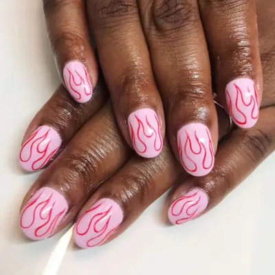 Light pink short round nails with outlines of fire in red.