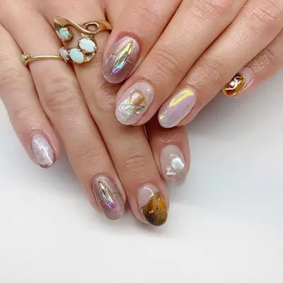 Person with pearl chrome nails adorned with 3D accents