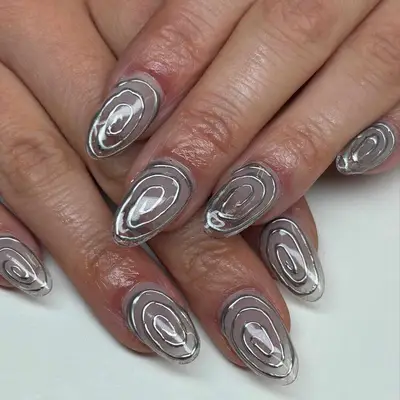 Person with see-through nails with swirly-design chrome details