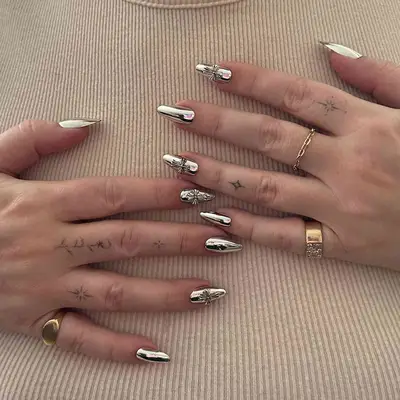 Person with silver Chrome Hearts-inspired nails
