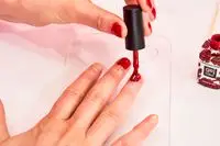 A person using red Londontown Lakur Enhanced Color Nail Polish to paint their nails