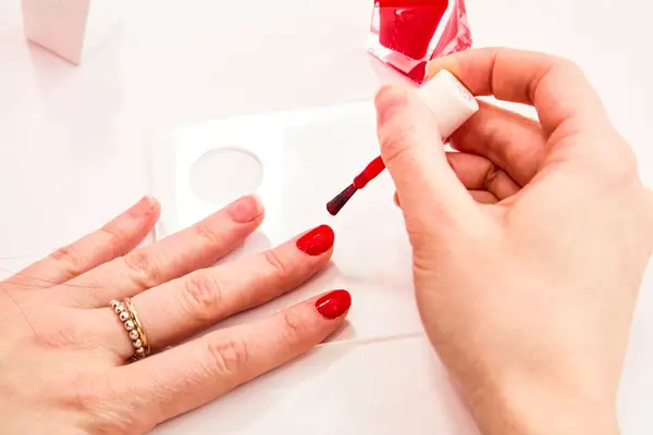 A person painting their nails with Essie Gel Couture Longwear Nail Polish