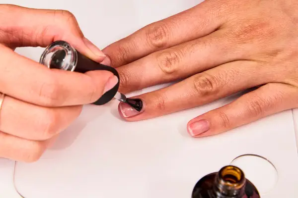 A person applying a base coat of Madam Glam Soak-Off Gel Polish to their ring finger nail