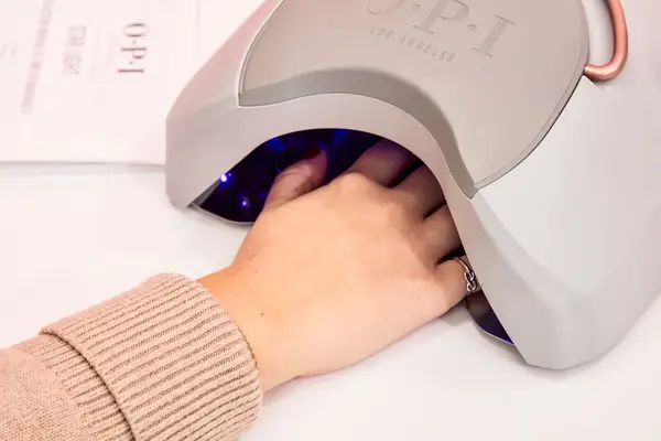 A hand in a UV gel lamp curing OPI GelColor Polish