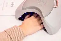 A hand in a UV gel lamp curing OPI GelColor Polish