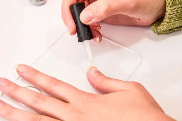 A close-up of a person applying the ORLY Gel FX Gel Nail Color base coat to their thumb nail