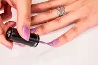 A manicured hand painting a pinky nail with Revlon ColorStay Gel Envy Longwear Nail Polish