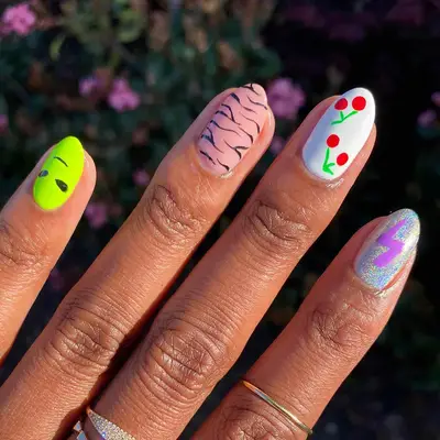 a mismatched manicure with emoji designs and a zebra nail