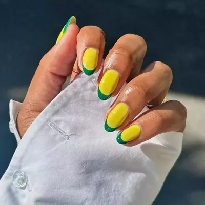 a french manicure with a yellow base and French tips in green