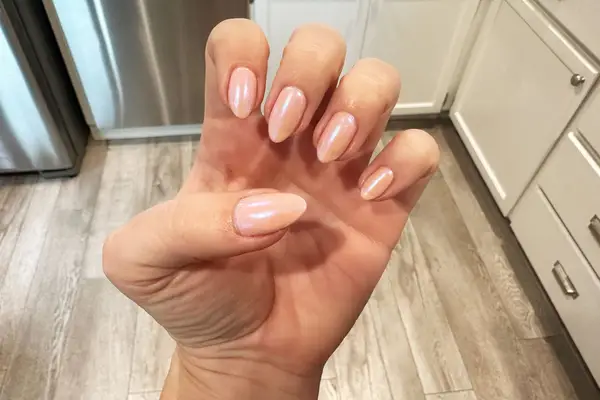 Hand with pink nails covered in cuticle oil 