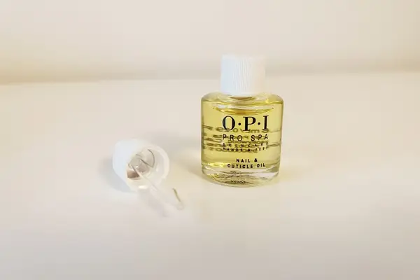 OPI ProSpa Nail & Cuticle Oil and its applicator dropper displayed on a beige background