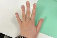 Close-up of a hand with nails covered in cuticle oil against a white and green background